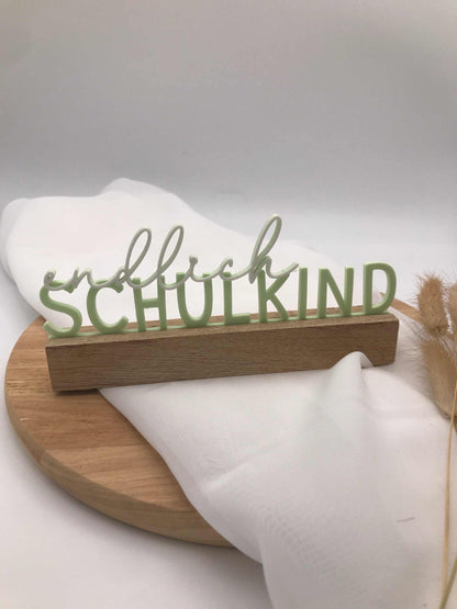 3D gedruckter Schriftzug "Endlich Schulkind" in verschiedenen Farben als Einschulungsdekoration auf Holzsockel