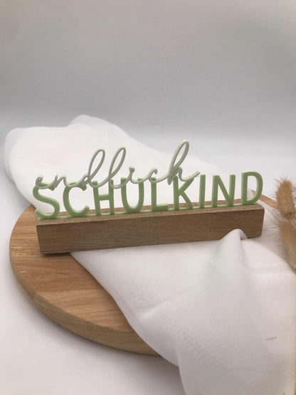 3D-gedruckter Aufsteller „Endlich Schulkind“ in grüner Farbe als Einschulungsdekoration auf Holzsockel
