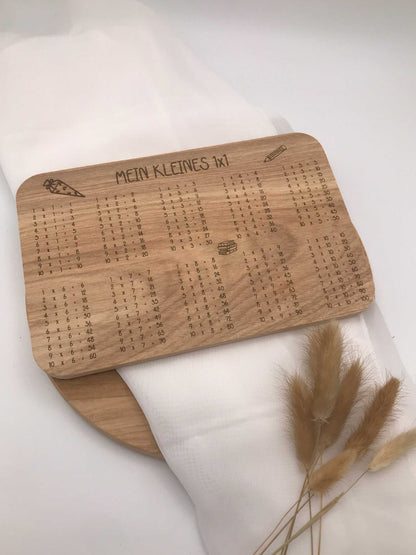 Frühstücksbrettchen aus Holz mit eingraviertem Einmaleins und dekorativen Motiven für die Einschulung