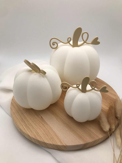 Drei weiße Dekokürbisse in verschiedenen Größen aus PLA-3D-Druck auf Holzplatte, zwei mit LED-Teelicht beleuchtet, herbstliche nachhaltige Tischdekoration