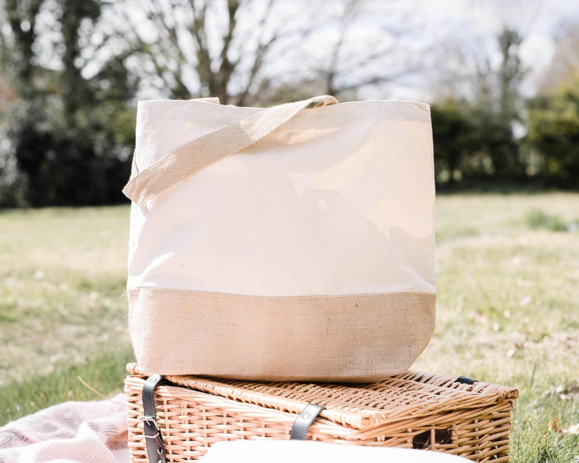 Personalisierte Jutetasche für Einkäufe im Freien auf einem Picknickkorb, umweltfreundlich und stilvoll.