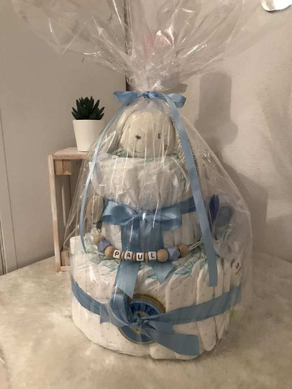 Diaper cake with pacifier chain wrapped in clear cellophane, ideal baby shower gift.