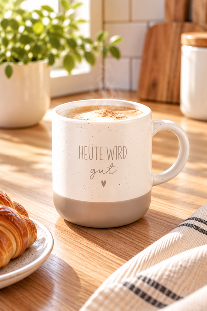 Kaffeetasse aus Keramik in Beige und Grau mit feinen Sprenkeln und dem Spruch „Heute wird gut“ samt Herz