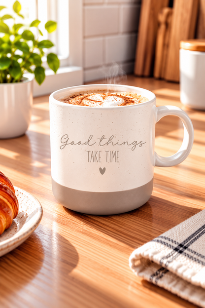 Kaffeetasse aus gesprenkelter Keramik in Beige und Grau mit dem Schriftzug „Good things take time“ und Herz