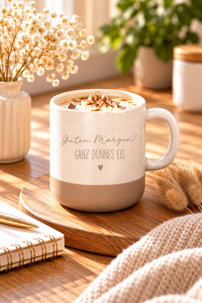 Kaffeetasse mit lustigem Spruch aus beiger, gesprenkelter Keramik mit grauem Boden und Aufdruck „Guten Morgen? Ganz dünnes Eis“