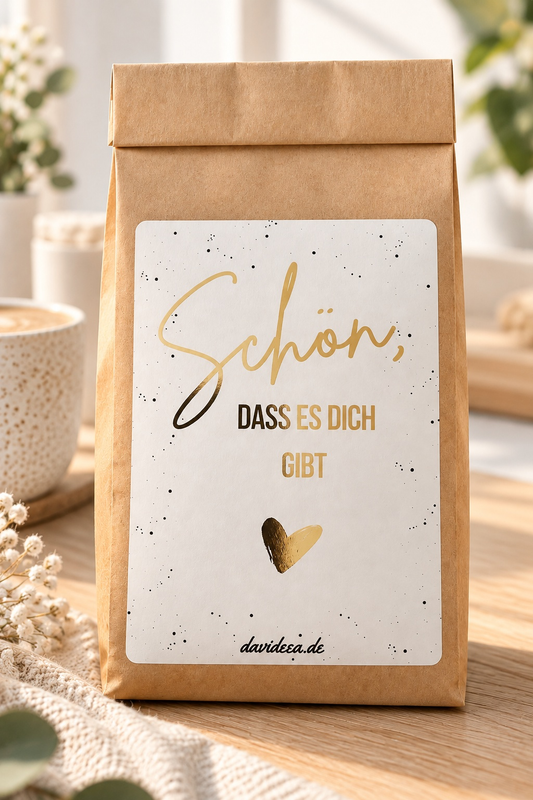Geschenktüte aus braunem Kraftpapier mit weißem Etikett, goldener Schrift „Schön, dass es dich gibt“ und Herz – kleine Aufmerksamkeit