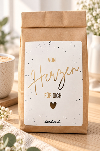 Geschenktüte aus braunem Kraftpapier mit weißem Etikett, goldener Schrift „Von Herzen für dich“ und Herz als kleine Aufmerksamkeit