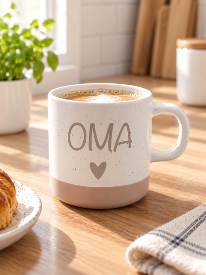 Tasse aus beiger Keramik mit braunem OMA-Schriftzug und Herz, gesprenkelter Oberfläche und schlichtem Henkel