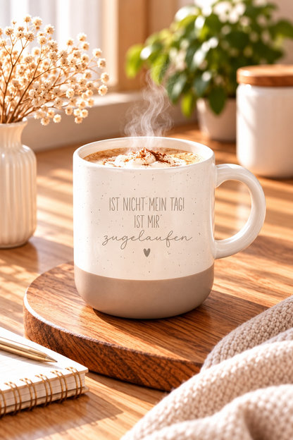 Tasse aus cremefarbener Keramik mit braunem Fuß, Spruch „Ist nicht mein Tag! Ist mir zugelaufen“ und kleinem Herz