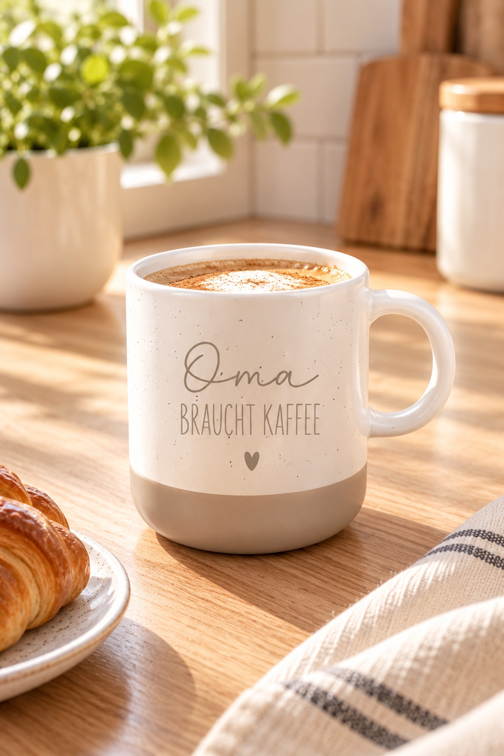 Tasse aus cremefarbener Keramik mit beigem Boden, feinen Sprenkeln und dem Aufdruck „Oma braucht Kaffee“ samt Herz